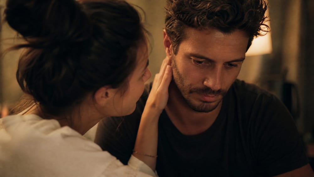 A woman tenderly touching her partner's neck as he looks uneasy, a man pulling back just as she gets closer